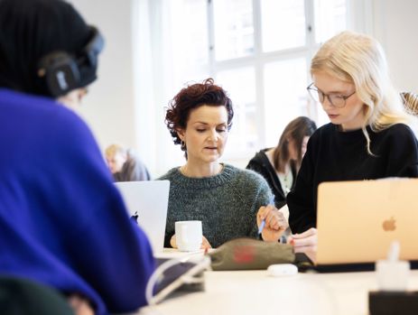 Gymnasielærer hjælper elev med en skriftlig opgave i klasselokalet 